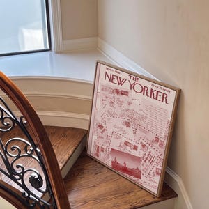 May include: A framed vintage New Yorker magazine cover from Sept. 17, 1966, in a wooden frame. The cover features a red and white design with illustrations and text. The framed print is leaning against a staircase.