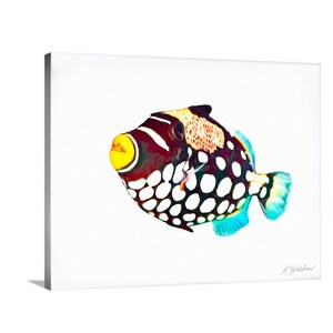 May include: A clown triggerfish art print on a white background. The fish features a dark body with large white spots on the lower half, a yellow mouth, and a patterned upper section. The fins are light blue, and a signature is visible in the corner.