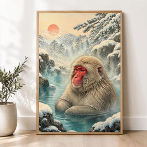 May include: A framed wall art print depicting a Japanese macaque with thick beige fur and a bright red face, sitting in a steaming natural hot spring. The background features snow-covered rocks, pine trees, distant mountains, and a pale sun.