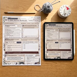 以下が含まれることがあります： The Hobby Graveyard Resurrectionというタイトルの印刷されたワークシート、同じドキュメントを表示するデジタルタブレット、筆付きの水彩絵の具セット、編み針が付いた灰色の毛糸玉、白いキッチンタイマー。