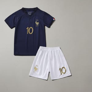 Pode incluir: Um conjunto de camisa e cal&ccedil;&atilde;o de futebol azul marinho. A camisa apresenta o n&uacute;mero 10 em dourado, um emblema de galo dourado e as letras FFF. O cal&ccedil;&atilde;o branco tamb&eacute;m exibe o n&uacute;mero 10 em dourado.