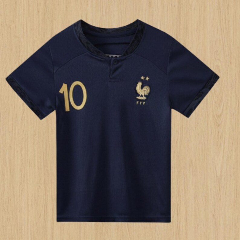 Pode incluir: Camisola de futebol azul marinho com o n&uacute;mero 10 em dourado na frente. A camisola apresenta um emblema dourado de um galo e estrelas, e as letras FFF. Tem mangas curtas e gola abotoada.