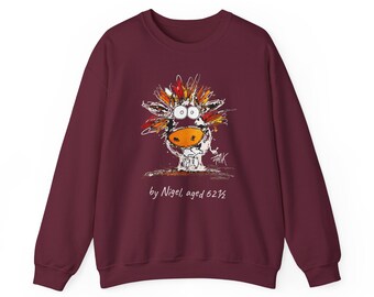 May include: A maroon long-sleeve sweatshirt featuring a graphic illustration of a stylized cow with a bright orange nose and colorful hair. Below the illustration, the text reads, "by Nigel, aged 62 1/2" in a white handwritten font.