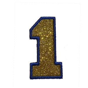 Könnte beinhalten: Eine goldene Glitzerzahl eins mit blauem Umriss. Die Zahl befindet sich auf weißem Hintergrund.