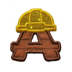 May include: Brown felt letter A with a yellow glitter construction worker hat on top.