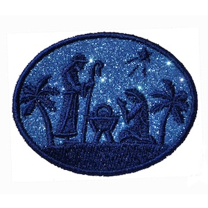 May include: Blue glitter oval Christmas bauble featuring a silhouette of the nativity scene, including Mary, Joseph, and baby Jesus in a manger. The bauble also includes a star and palm trees.
