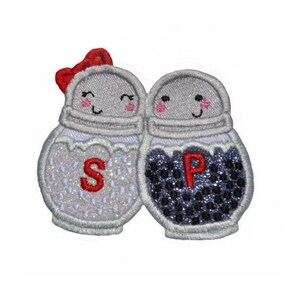 May include: A white salt shaker with a red bow and a black pepper shaker with a smiling face. Both shakers have the letters "S" and "P" on them.