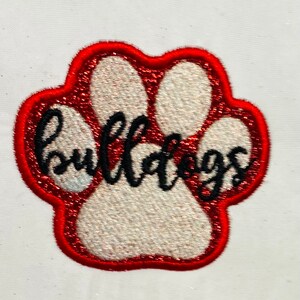 Könnte beinhalten: Ein roter und weißer Pfotenabdruck mit dem Wort "Bulldogs" in schwarzer Kursivschrift.