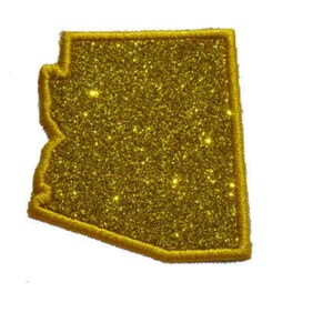 Könnte beinhalten: Ein goldfarbener, glitzernder Stoffaufnäher in der Form des US-Bundesstaates Arizona. Der Aufnäher weist eine dichte, funkelnde Textur auf der gesamten Oberfläche auf und ist mit einem passenden goldfarbenen Stickrand am Außenrand versehen.
