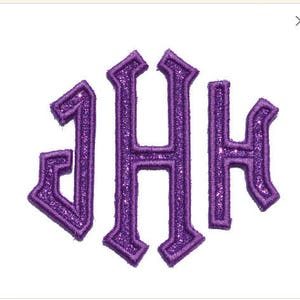 Könnte beinhalten: Ein lila Glitzer-Monogramm mit den Buchstaben J, H und H in einer stilisierten gotischen Schriftart. Die Buchstaben sind mit einem schimmernden, strukturierten Effekt gestickt, vor einem sauberen weißen Hintergrund. Ideal für personalisierte Geschenke.