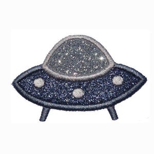 May include: A sparkly, embroidered patch in the shape of a UFO. The flying saucer has a navy blue body with silver glitter and three white circular lights. The top dome is silver glitter, and it has three small legs.