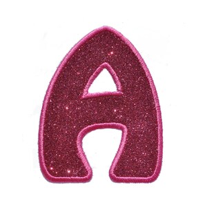 Könnte beinhalten: Ein pinkfarbener Glitzer-Aufkleber in Form des Buchstabens A.