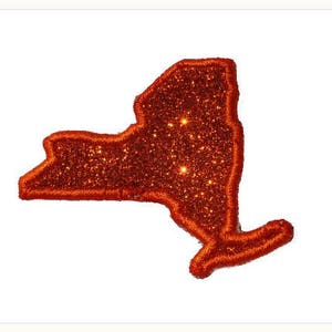 May include: Orange glitter outline of the state of New York. The glitter is a fine, sparkly texture.