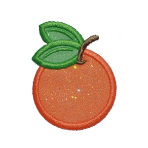 Puede incluir: Una fruta naranja brillante con hojas verdes. La naranja es una aplicación de fieltro con purpurina.