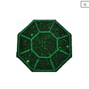 以下が含まれることがあります： 大きなファセットカットの宝石の形をした、緑色のグリッターアイロン接着パッチです。