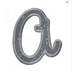 May include: A silver glitter iron-on patch in the shape of the letter "a".