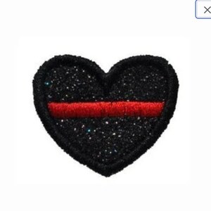 May include: Black heart-shaped patch with a red stripe across the center. The patch is covered in glitter.