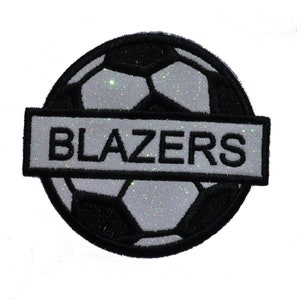 May include: A black and white football with glitter, with the word "BLAZERS" in a white banner across the middle.