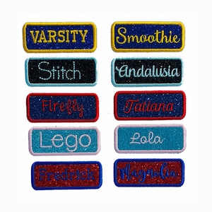 Puede incluir: Diez parches termoadhesivos coloridos con purpurina y texto bordado. Los parches incluyen las palabras: Varsity, Smoothie, Stitch, Andalusia, Firefly, Tatiana, Lego, Lola, Fredrick y Magnolia.