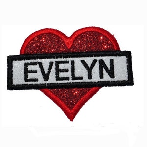 May include: Red glitter heart with a black and white banner that reads "EVELYN".
