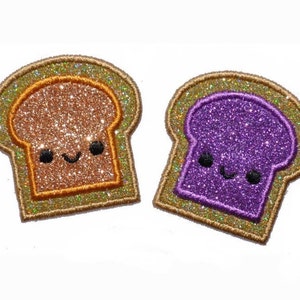 Peut inclure: Deux patchs en feutre recouverts de paillettes en forme de tranches de pain. Une tranche est brune avec un visage heureux et l'autre est violette avec un visage heureux.
