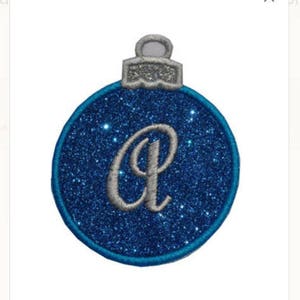 May include: A blue glitter Christmas bauble with a silver letter "A" in the centre.
