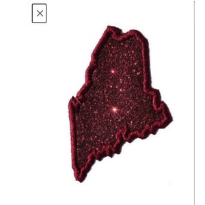 May include: A red glitter outline of the state of Maine. The glitter is a dark red colour and the outline is a slightly lighter red.