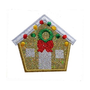 Op de afbeelding: Een gouden glitter gingerbread huis met een rode strik en een groene krans. Het huis heeft witte versieringen en rode en gele snoepjes.
