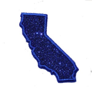 May include: A glittery dark blue embroidered patch in the shape of the state of California. The patch features a dense, sparkling texture throughout its surface and is finished with a matching dark blue stitched border along the entire edge.