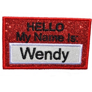 Op de afbeelding: Rood glitter naamkaartje met witte rand en de tekst "Hello My Name Is: Wendy".