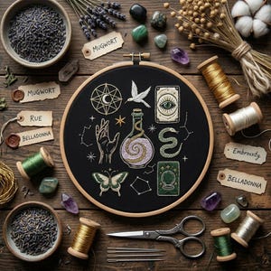 Puede incluir: Un bastidor de bordado con tela negra con símbolos místicos, una mariposa y una serpiente. La imagen incluye carretes de hilo, hierbas secas, cristales y etiquetas con las palabras "Mugwort", "Rue" y "Belladonna", todo dispuesto sobre una superficie de madera.