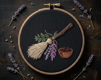 May include: An embroidered artwork featuring a witch's broom, lavender, and a small bowl of berries. The design is set against a black fabric within a wooden embroidery hoop. Sprigs of lavender are arranged around the hoop on a dark wooden surface.