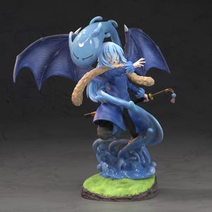 May include: A detailed figurine of a character with blue hair and clothing, featuring large blue wings and a light blue slime companion. The figure stands on a green and brown base, holding a staff with colorful accents.
