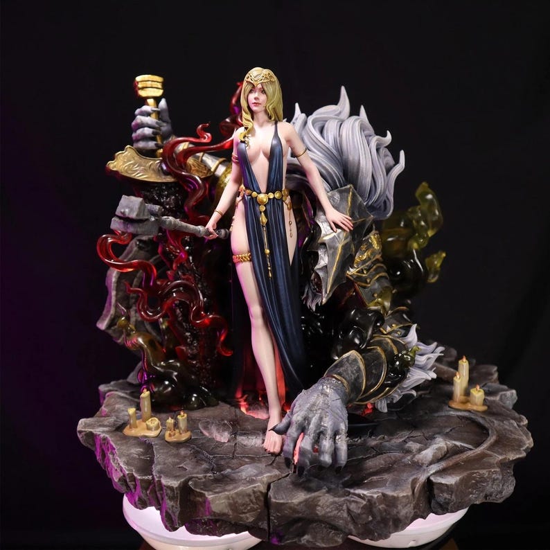 May include: A detailed figurine featuring a woman in a flowing blue dress and gold accents, standing before a figure in dark armor. The base is a rocky platform with candles, and the overall design has a fantasy theme.