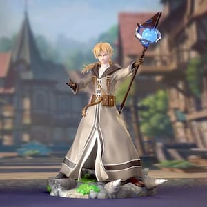 May include: A detailed figurine of a character in a long, light gray robe with brown accents, holding a staff with a glowing blue orb. The figure has blonde hair and is posed in front of a blurred background of buildings.