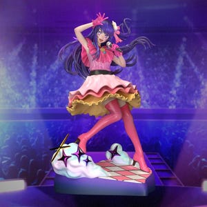 May include: A figurine of a female anime character in a pink and yellow dress, holding a microphone. The figure is on a stage-like base with a cloud and star design. The background is a blurred purple.