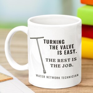 May include: A white ceramic mug featuring a graphic of a T-handle valve key and the black text: TURNING THE VALVE IS EASY. THE REST IS THE JOB. WATER NETWORK TECHNICIAN. The mug has a standard handle and a smooth, cylindrical body design.