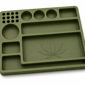 Puede incluir: Una bandeja para liar de color verde oliva con m&uacute;ltiples compartimentos y un dise&ntilde;o de hoja de cannabis. La bandeja presenta secciones circulares y rectangulares de varios tama&ntilde;os para almacenamiento y organizaci&oacute;n. La bandeja est&aacute; hecha de un material duradero.