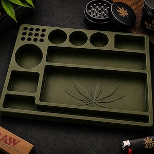 Puede incluir: Bandeja para liar verde oliva con varios compartimentos y un dise&ntilde;o de hoja de cannabis. Incluye un molinillo, un recipiente con el logotipo de una hoja de cannabis y un encendedor con el n&uacute;mero 420.