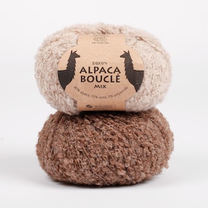 May include: Two balls of Drops Alpaca Boucle Mix yarn. The top ball is light beige, and the bottom ball is brown. The label reads "80% alpaca, 15% wool, 5% polyamide". The yarn is for knitting and crocheting.