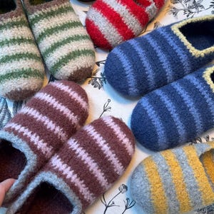 May include: A selection of handmade wool slippers with striped patterns. The slippers feature colours such as green, red, blue, brown, and yellow. These cosy slippers are designed for indoor use and offer a comfortable fit.