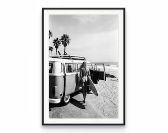 Può includere: Una stampa artistica da parete incorniciata in bianco e nero che raffigura un furgone vintage parcheggiato su una spiaggia sabbiosa con palme sullo sfondo. Una figura si trova accanto alla porta laterale aperta del furgone con una tavola da surf.