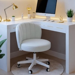 May include: A modern home office setup with a white desk and chair, a computer, and floating shelves. The shelves are illuminated with LED lights and decorated with plants, books, and gold accents. A gold desk lamp and a potted plant are on the desk.