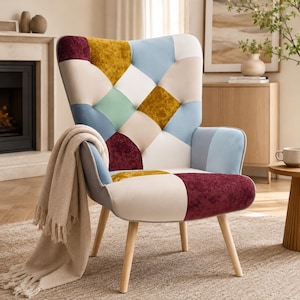 May include: A patchwork armchair with a high back and wooden legs. The chair features a variety of colors, including blue, yellow, burgundy, and cream. A beige throw blanket is draped over the arm. The chair is in a living room setting.