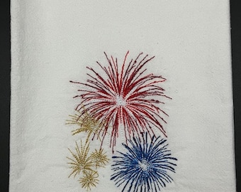 May include: White kitchen towel with embroidered red, white, and blue fireworks.