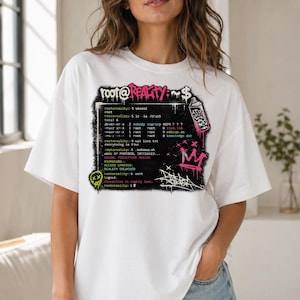 以下が含まれることがあります： グラフィックデザインの白いTシャツ。「root@REALITY:~$"のテキストとコード行が特徴です。ピンク、黒、白のグラフィティスタイルの要素には、王冠とスプレー缶が含まれています。