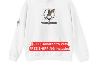 Puede incluir: Una sudadera blanca con capucha y manga larga que presenta un gráfico central de un lazo y una pluma estilográfica rodeados por un círculo de estrellas. El texto "TREASON AND FREEDOM" aparece debajo del gráfico y un pequeño emblema de la bandera estadounidense está en la manga.
