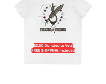 Puede incluir: Una camiseta blanca de manga corta con un gráfico en la parte posterior. El diseño incluye una pluma estilográfica marrón y un lazo negro, rodeados por un círculo de estrellas rojas y azules. El texto dice TREASON AND FREEDOM en negrita.