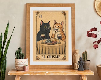 May include: A framed print featuring a tarot-style card labeled 21 EL CHISME. The illustration shows a black cat and an orange tabby cat sitting at a round table with two glasses of red wine, a plate of cheese, and sardines on a wooden board.