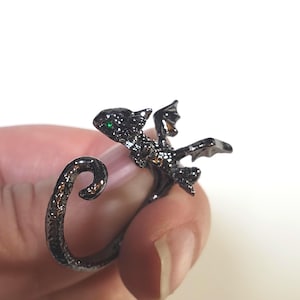 Op de afbeelding: Een zwarte drakenring met groene ogen. De staart van de draak krult om de vinger.